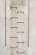 Concrete wall with a metal climbing ladder and railings attached to the wall.