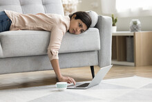 Overworked Exhausted Indian Freelancer Woman Lying On Sofa With Face On Seat, Using Laptop Computer Placed With Cup Of Coffee On Floor, Having Problems With Deadline, Feeling Tired, Fatigue