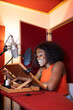© ADDICTIVE STOCK - Smiling young black woman sitting at desk and recording podcast