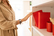 © ADDICTIVE STOCK - Crop woman with ring binder and cup in shelf at furniture store
