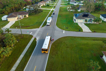 Wall Mural - Aerial view of american yellow school bus picking up children at sidewalk bus stop for their lessongs in early morning. Public transportation in the USA