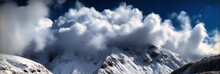 Clouds And Snow Fall Over Mountains With A Blue Sky