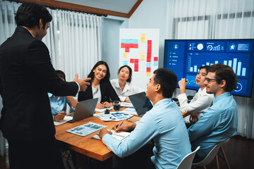 Diverse group of business analyst team analyzing financial data report. Finance data analysis chart and graph dashboard show on TV screen in meeting room for strategic marketing planning. Habiliment