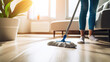 Low section of young woman cleaning floor with wet mop at home.