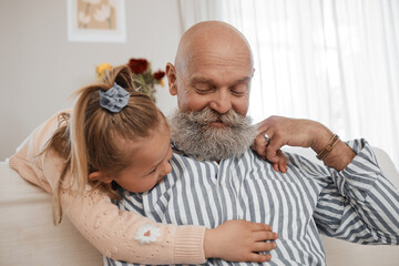 Wall Mural - Love, couch, and child hug grandfather in a home for bonding, care and relax together in living room for fun. Senior, sofa and elderly person or grandparent with girl kid as family on retirement