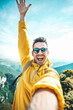 © Davide Angelini - Young hiker man taking vertical selfie portrait on the top of mountain - Happy guy smiling at camera - Tourism, sport life style and social media influencer concept