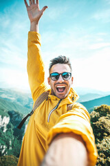 Wall Mural - Young hiker man taking vertical selfie portrait on the top of mountain - Happy guy smiling at camera - Tourism, sport life style and social media influencer concept