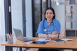 © Tj - Portrait of Asian female doctor working on the desk and smiling