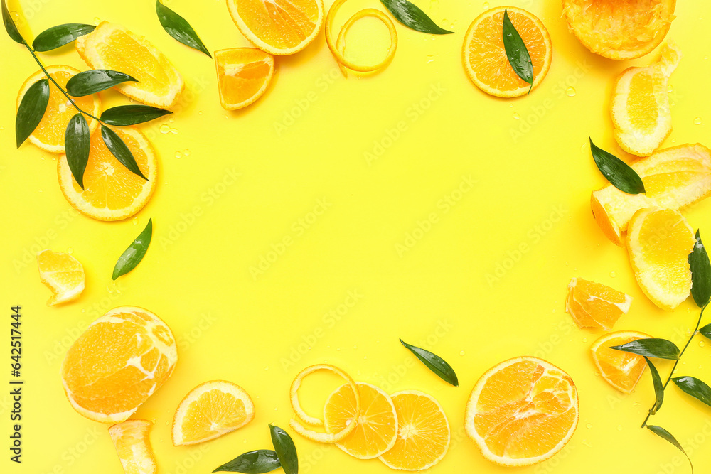 Frame made of orange slices with leaves on yellow background