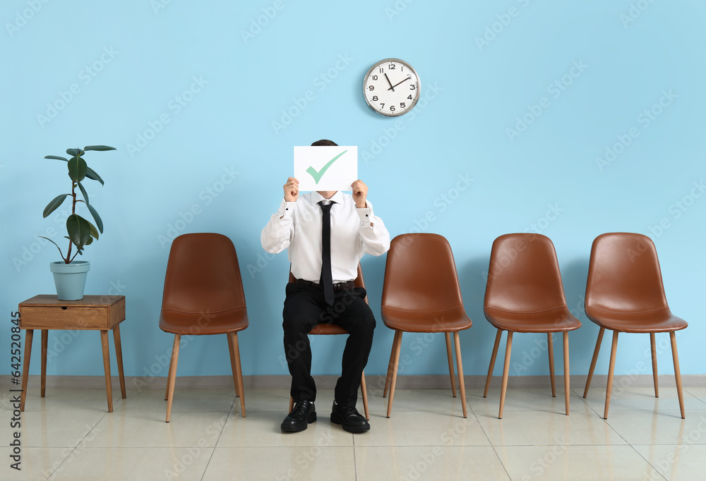 Male applicant holding paper with check mark in room