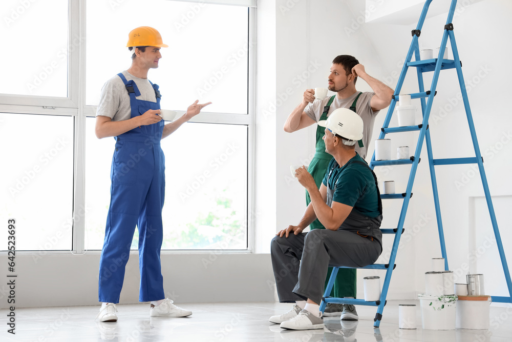 Team of male builders during coffee break in room