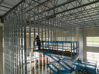 construction worker on a scissor lift working on steel studs