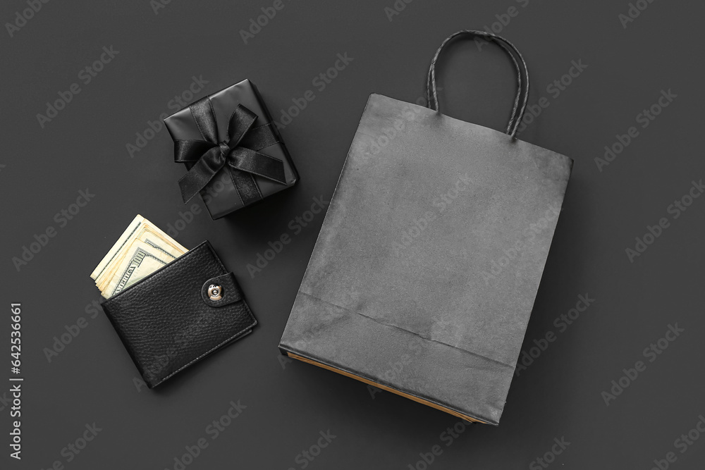 Shopping bag, gift box and wallet with money on black background. Black Friday concept
