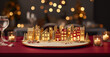© Viks_jin - Small illuminated miniature village toy on bokeh Christmas table with candles. Cute Christmas small town with snowy houses. Christmas Holidays. Christmas Card. digital ai
