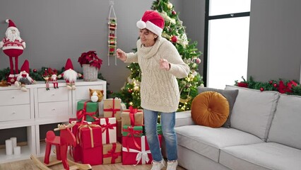 Wall Mural - Mature hispanic woman dancing by christmas tree at home