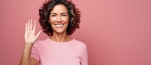 Smiling Woman Happily Waving Welcoming Or Saying Goodbye By Pink Wall