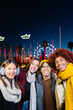 © Xavier Lorenzo - Vertical portrait of diverse group of young people having fun together outdoors. Millennial friends enjoying winter vacation visiting christmas market at night. Friendship and travel concept.