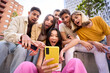 © CarlosBarquero - Group young people surprised watching something on phone. Multiracial friends sitting outdoor using mobile together. Concept of friendship social networks and technology addiction in new generations.