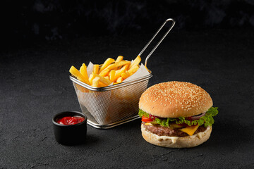 Wall Mural - Classic cheeseburger and french fries on black background. Fast food restaurant