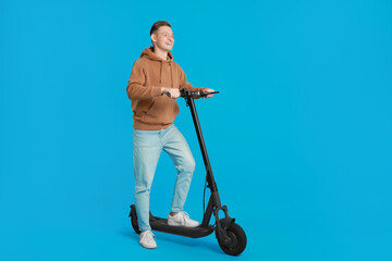 Poster - Happy man with modern electric kick scooter on light blue background