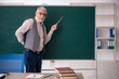 © Elnur - Old male teacher in front of green board