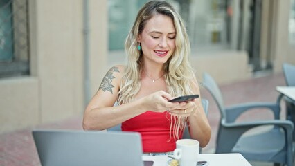 Poster - Young blonde woman make photo to coffee by smartphone sitting on table at coffee shop terrace