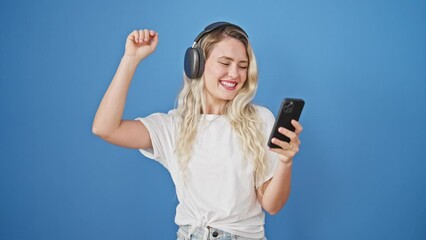 Poster - Young blonde woman listening to music and dancing over isolated blue background