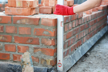 Sticker - Bricklayer using a spirit level to check new brick foundation wall. Brick house wall foundation with bitumen wateproof barrier.