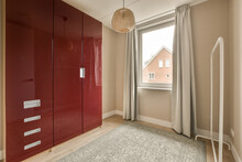 A Bedroom With Red Cupboards And White Curtains On The Window Sies, In Front Of An Open Door