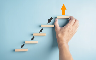 Aufkleber - Hand holding wooden block orange arrow and different direction facing opposite direction with black arrow for business disruption and technology transformation and different thinking idea
