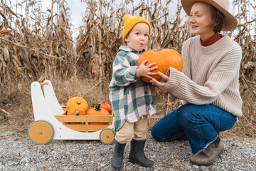 Mother and children playing together in pumpkin patch in autumn
