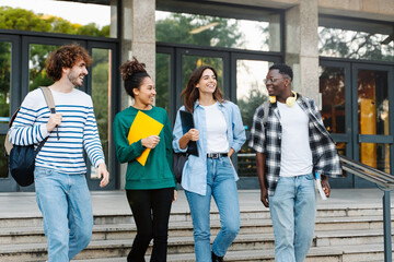 Group of Latin and African American college student friends walking outside University building 