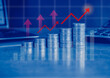 © tendo23 - Stack of money coin on office desk with chart, trading graph and up arrow with blue color filter. Business and financial concept.