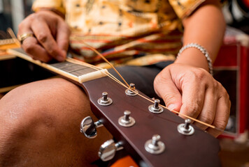 Wall Mural - Young musician changing strings on a classical guitar in a guitar shop