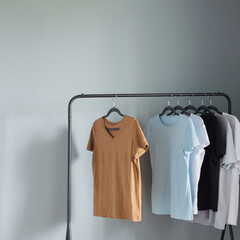 Canvas Print - T-shirts of neutral colors on  black hanger against  gray wall