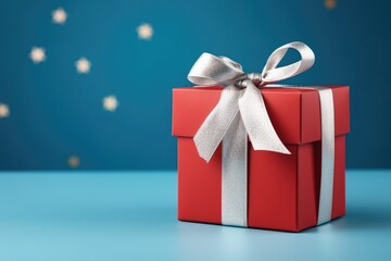 Red gift box with white ribbon on blue backdrop Concept and celebration image Space to write