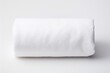 A white bath towel neatly rolled up set against a plain white background
