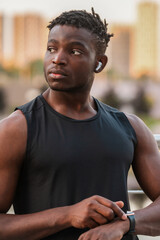 Canvas Print - Confident African man in sportswear using smart watch while during his sport training outdoors