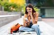 © Prostock-studio - Happy young woman university student using smartphone app sitting outdoors