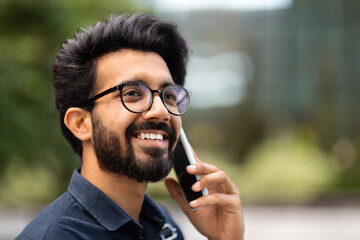 Wall Mural - Handsome young indian man talking on cellphone while walking