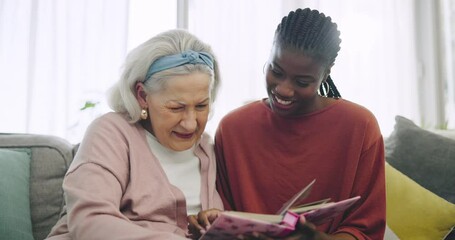 Wall Mural - Photo album, assisted living and an old woman laughing with her caregiver on a sofa in the living room. Smile, funny and senior resident looking at a memory with an african nurse in a retirement home