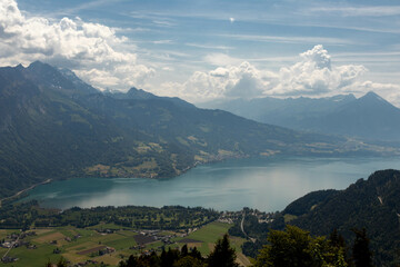 Wall Mural - The Swiss Alps with Buildings Sitting Along the Hills and Mountains and a Lake in the background in Switzerland in Summer