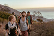 © Marko Geber - Young and diverse group of people and hikers hiking on a ridge overlooking the ocean and a beautiful sunset in South Africa