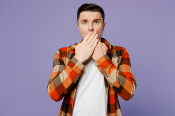 Wall Mural - Young shocked astonished sad scared man he wears checkered shirt white t-shirt casual clothes cover mouth with hand isolated on plain pastel light purple background studio portrait. Lifestyle concept.