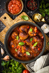 Sticker - Meatballs in tomato sauce in a skillet on dark kitchen table with ingredients. Top view with copy space.