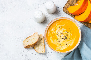 Wall Mural - Pumpkin soup puree with cream in the bowl. Top view image at white table.