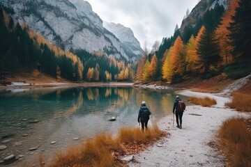 Wall Mural - two people walking on a path next to a body of water surrounded by trees in the background is a mountain range