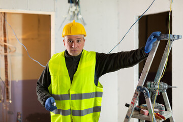 Wall Mural - Caucasian repair man standing in apartment at stepladder and looking at camera.