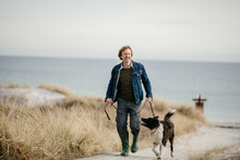Middle Aged Man Walking His Dog On The Beach