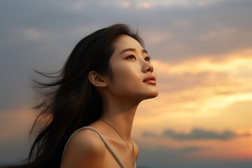 Canvas Print - Young woman looking up at the sky at sunset